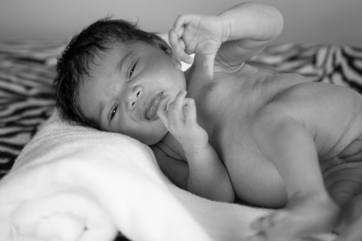 Newborn portrait with calm expression and soft black-and-white finish.
