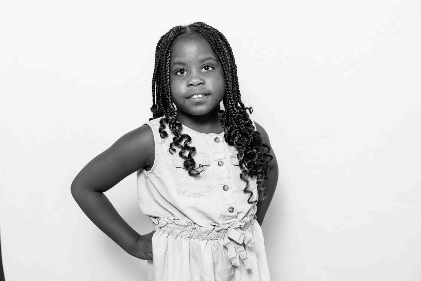 Girl braids white dress, hand on hip, B&W.