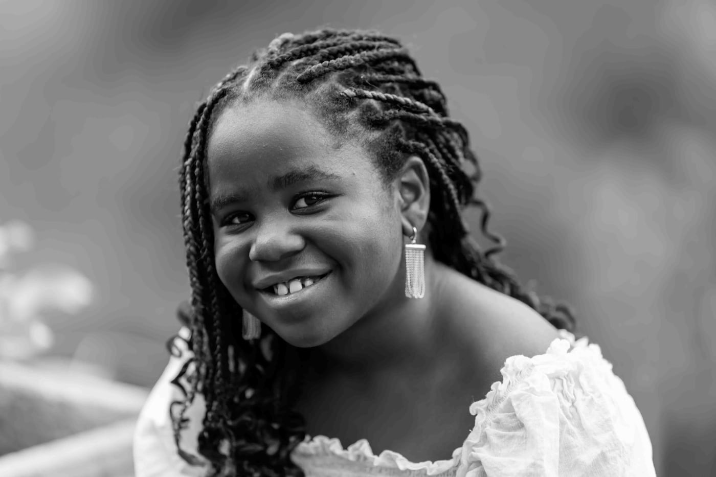 Girl braids, earrings, warm smile, B&W.