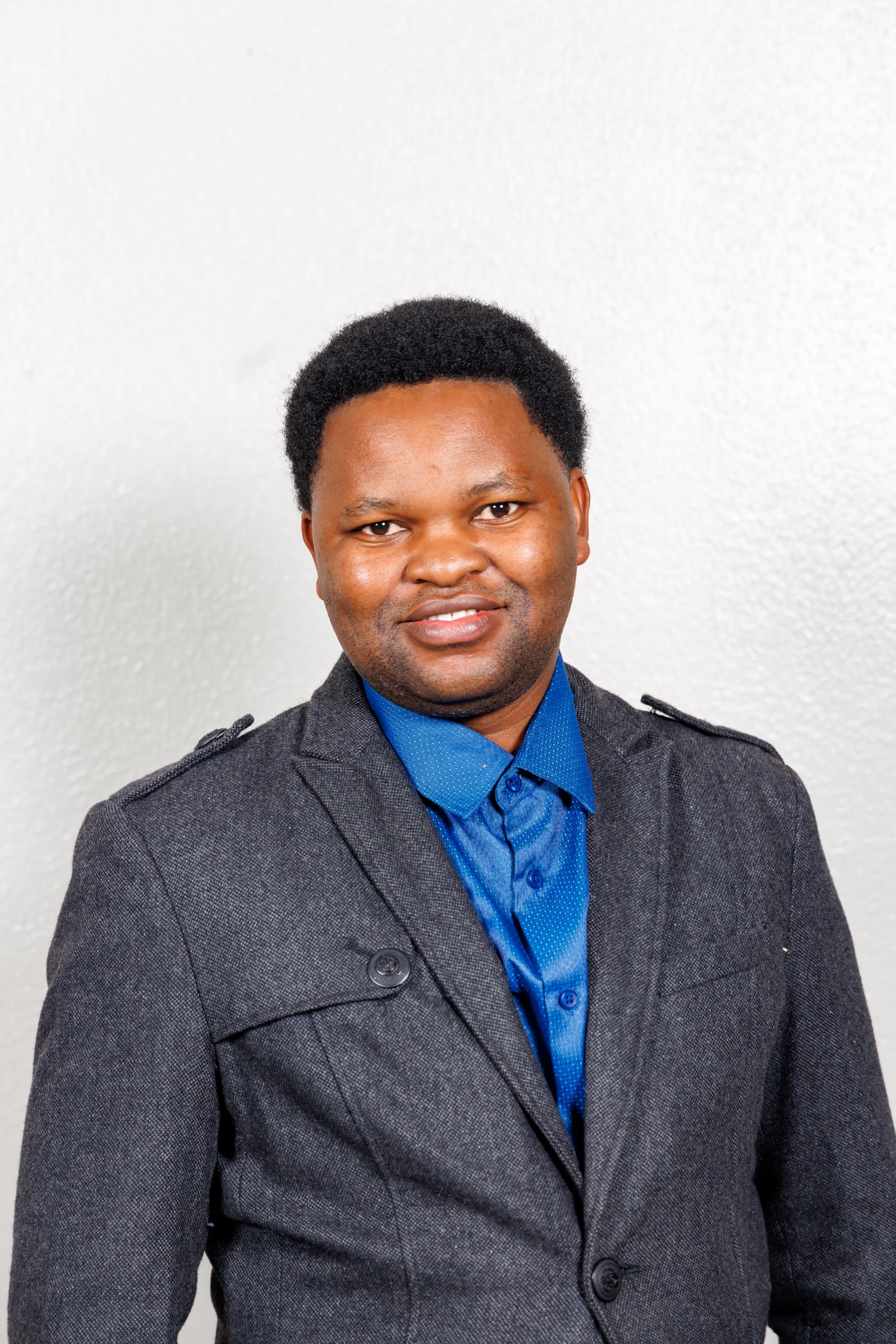 Man gray jacket, blue shirt, headshot.