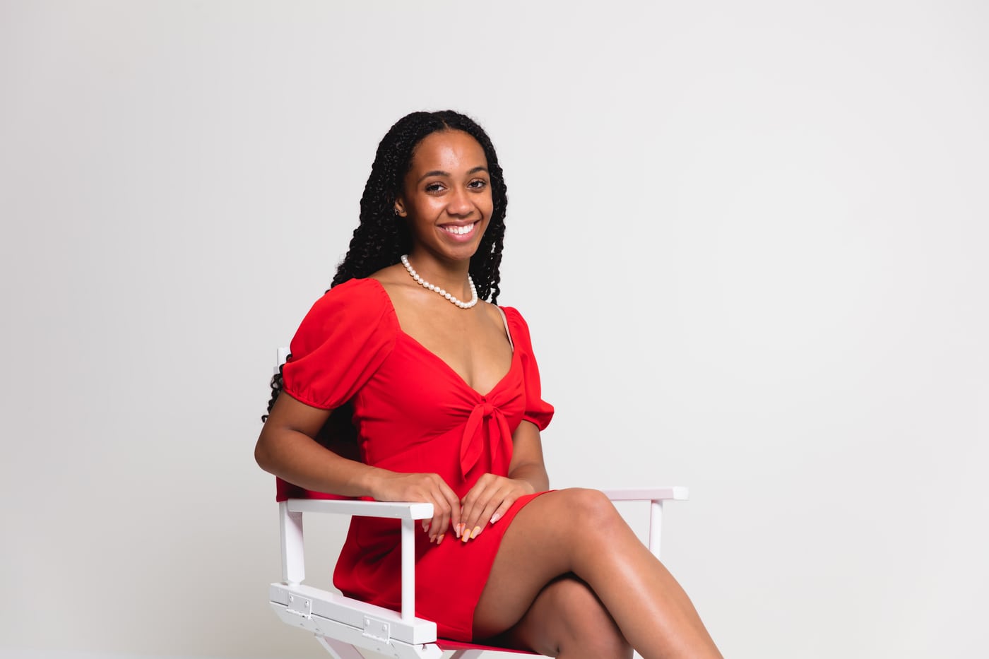 Woman red dress seated, tree bg, elegant.