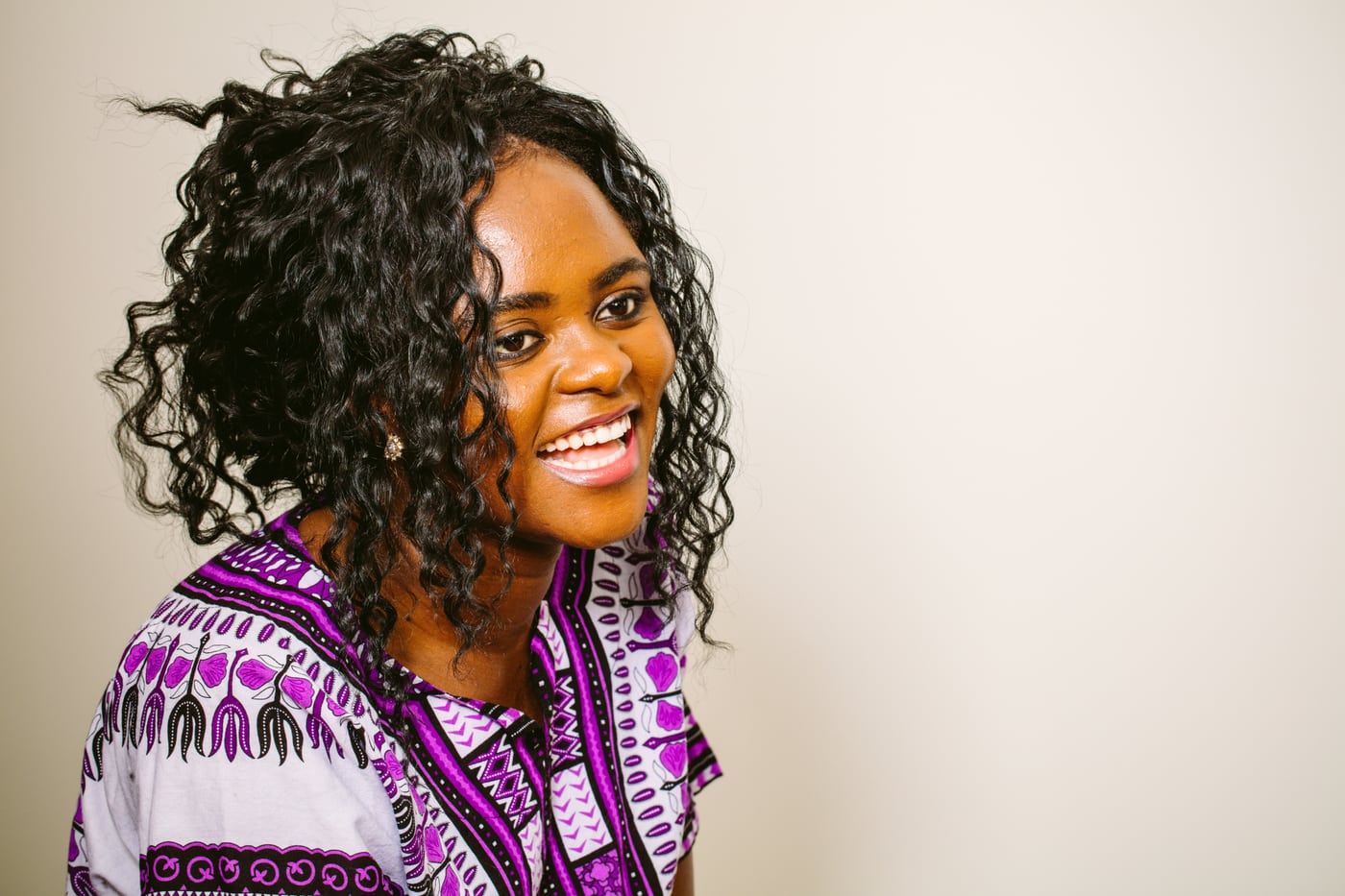 Woman in dashiki, curly hair, laughing, joyful cultural.
