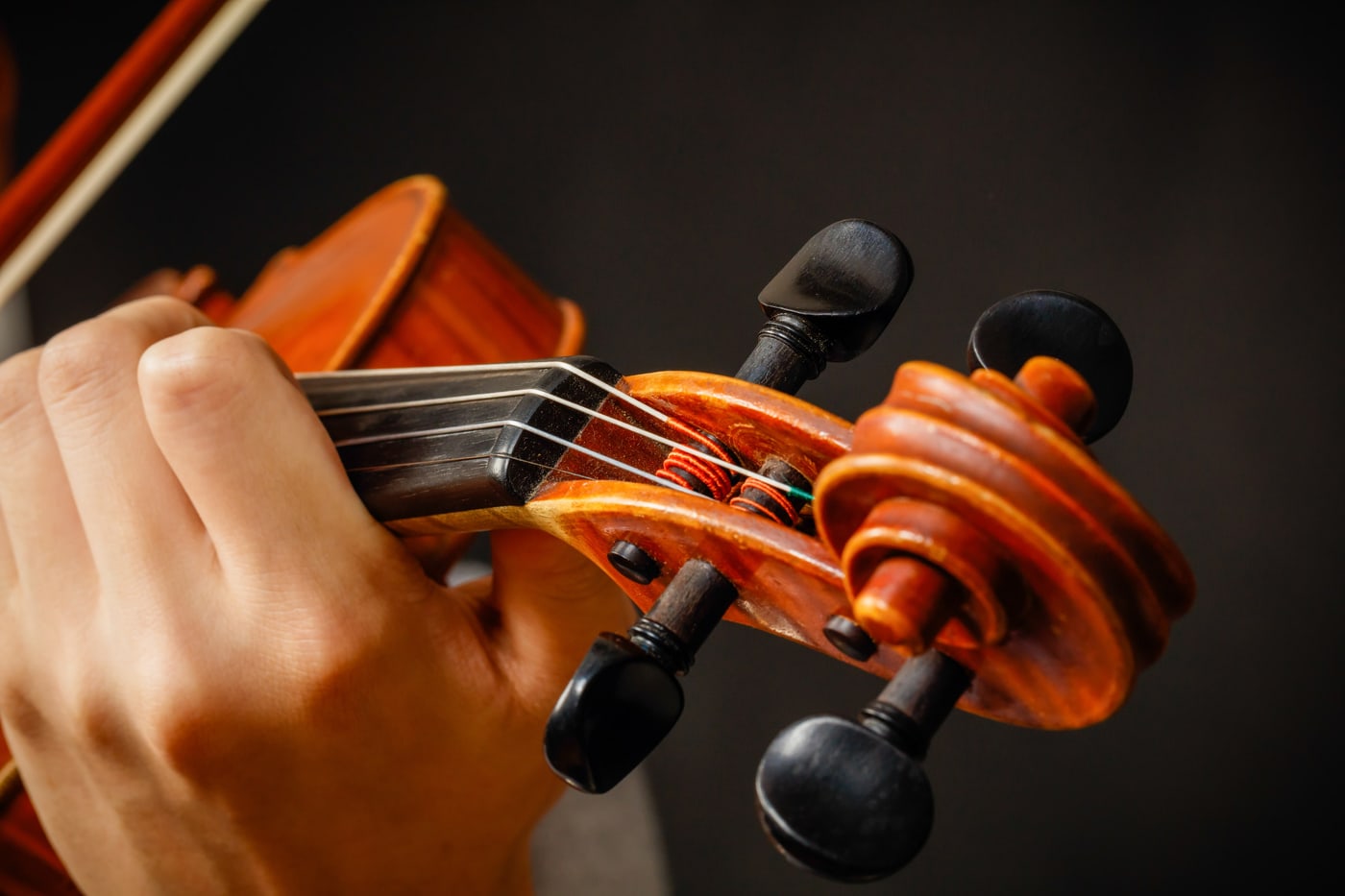 Senior musician detail with violin strings and hands.