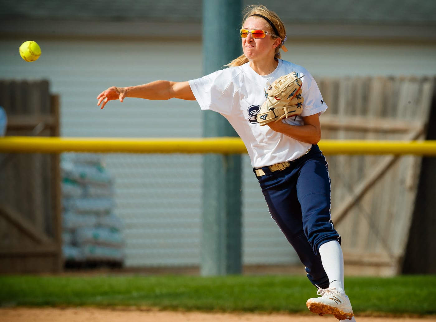 Softball fielder throwing, ball airborne, action.